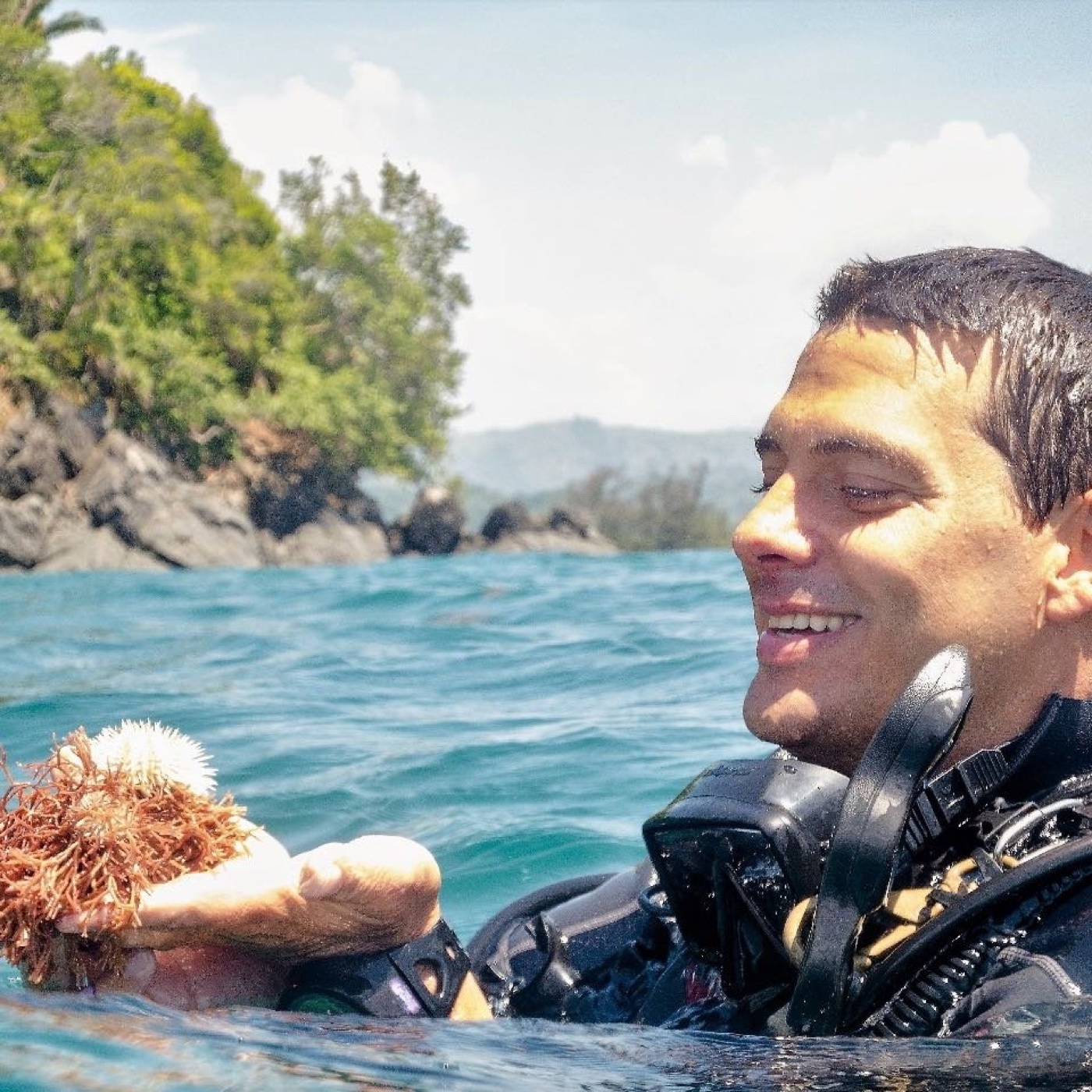 Antal Börcsök at the surface in dive gear off Tela, Honduras, holding a piece of coral