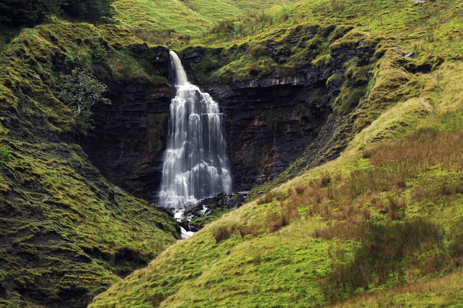 A waterfall falling into a green horseshoe valley in Sligo