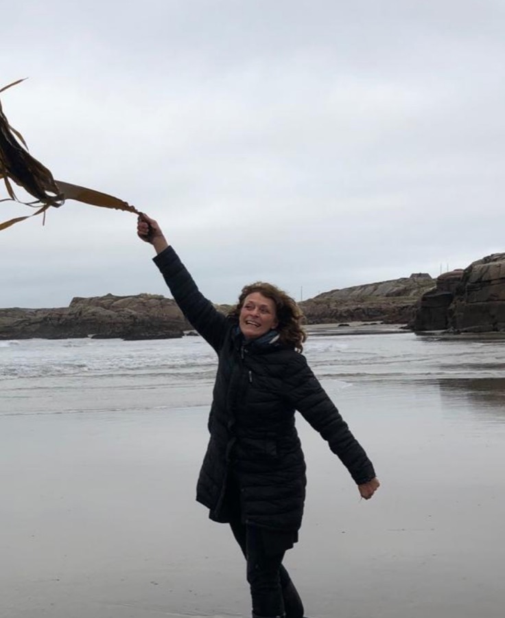 Beatrix, marine biologist, holding a frond of kelp on a Donegal beach