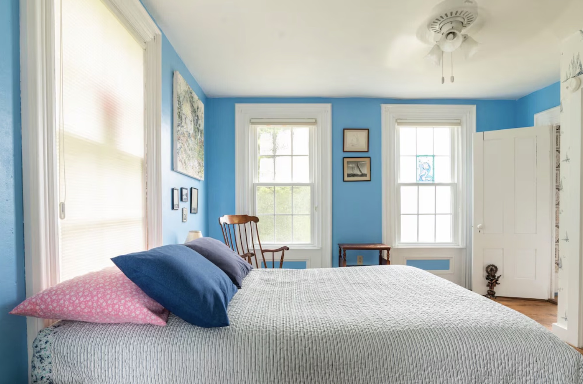 A bright blue bedroom with tall sash windows at the Maine retreat house