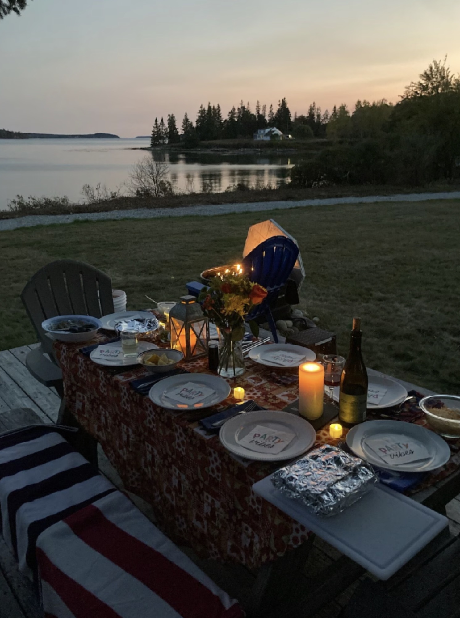 A candlelit dinner table set beside the water at sunset