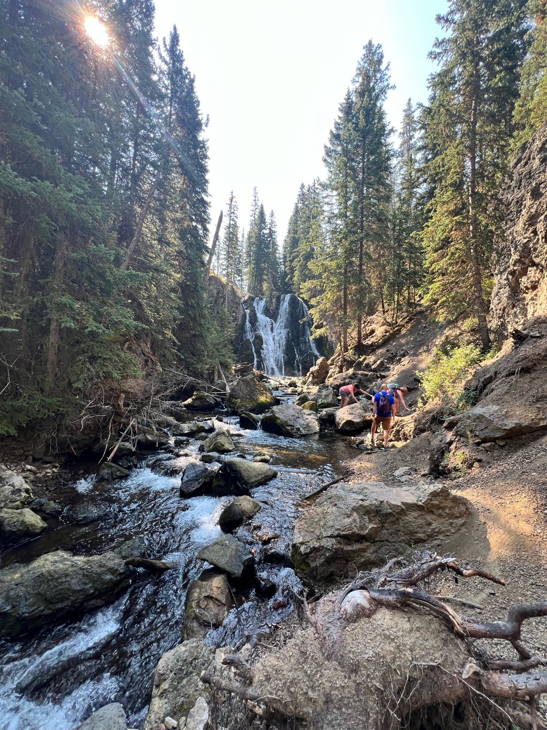 Hikers beside a creek and waterfall in Montana