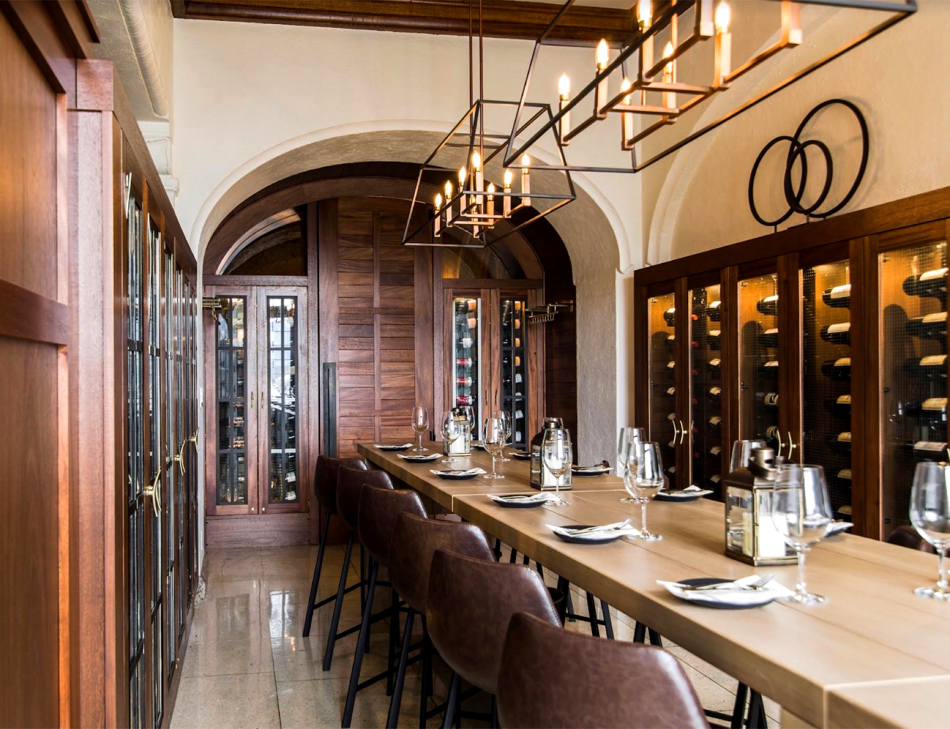 Long dining table set beneath vaulted timber and wine racks at the retreat property