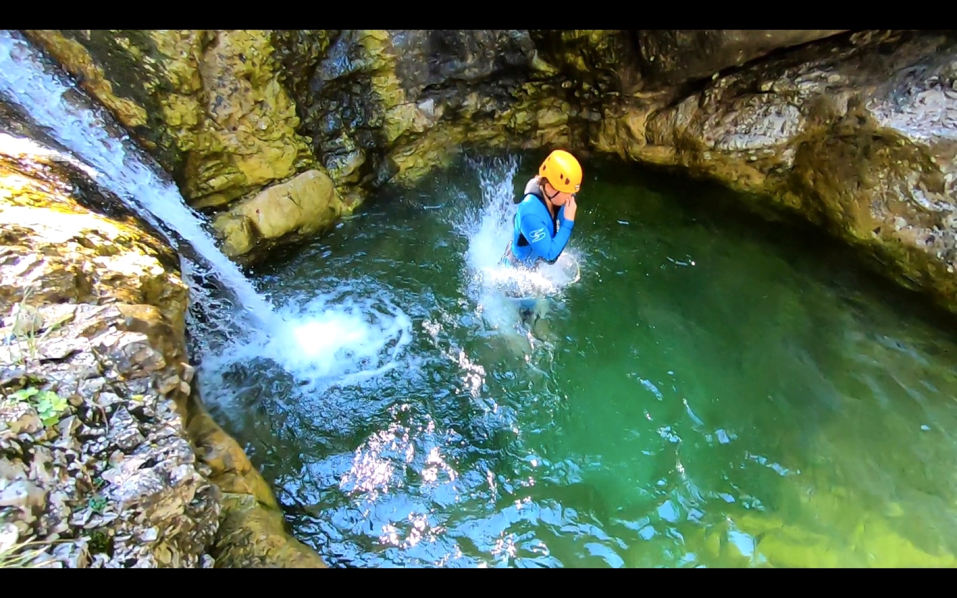 Canyoning down a waterfall into bright green water in the Soča Valley