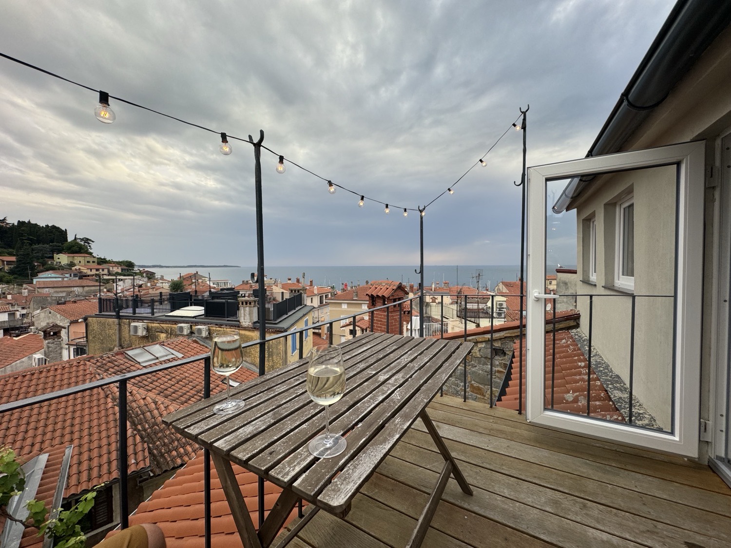 A terrace table under string lights above the rooftops, Slovenian coast