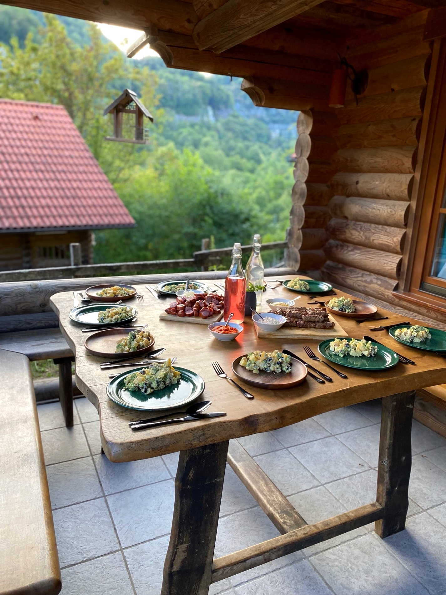 A long table set for dinner outdoors under a timber roof in the Soča Valley