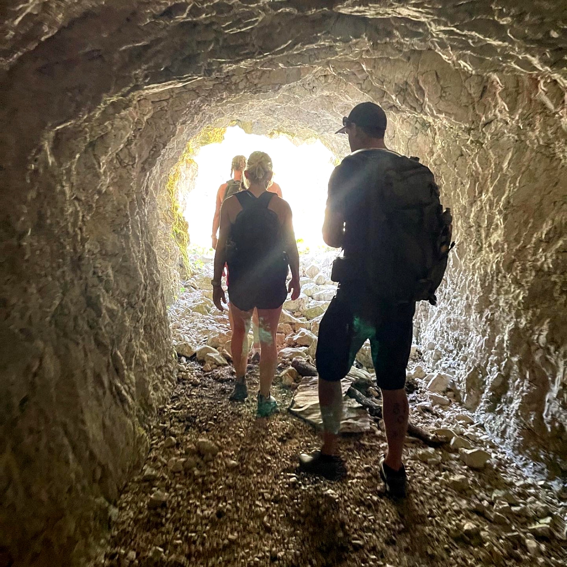 Hikers passing through a mountain tunnel on the Krasji vrh trail, Julian Alps