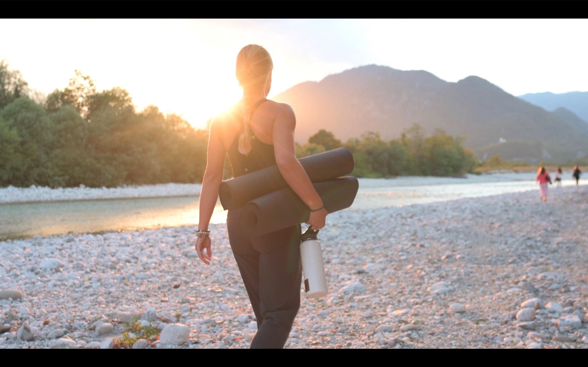 Walking back along the Soča riverbed with a yoga mat at sunset
