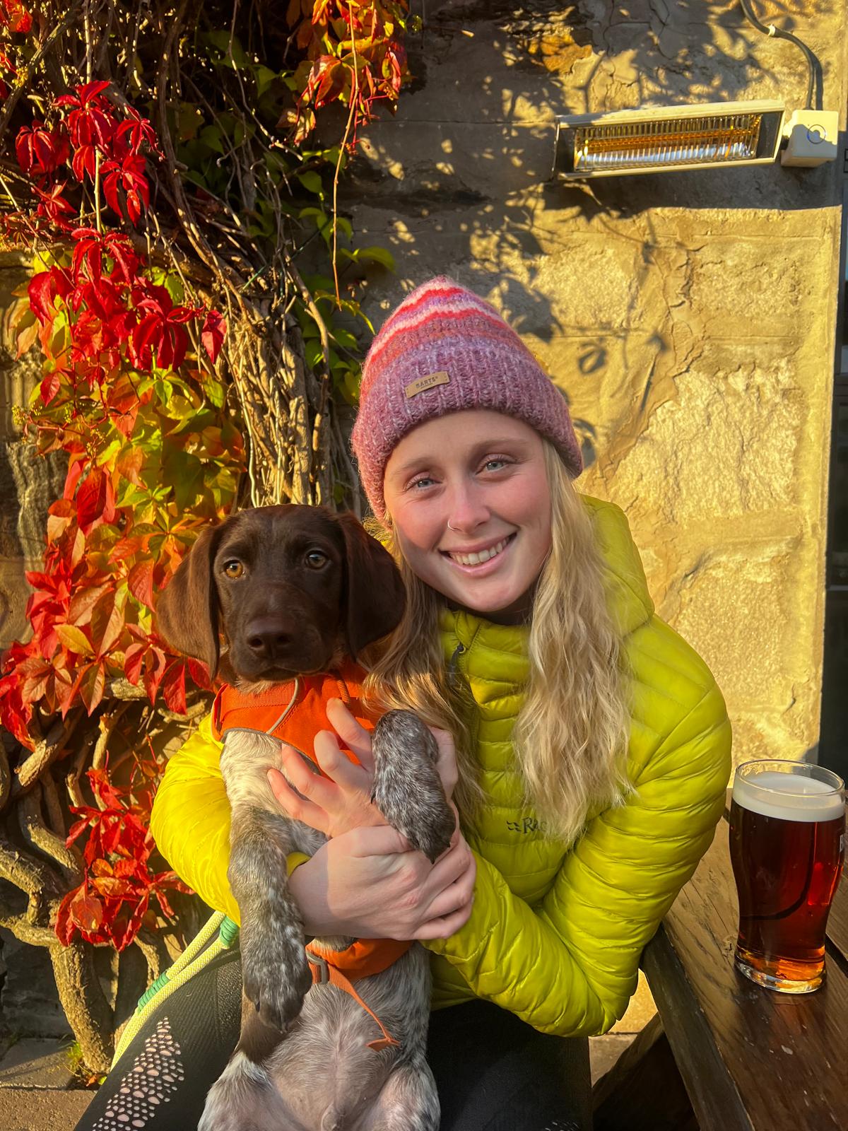 Laura, retreat host and outdoor guide, with her dog among autumn leaves